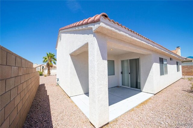 rear view of house with a tile roof, a patio area, a fenced backyard, and stucco siding