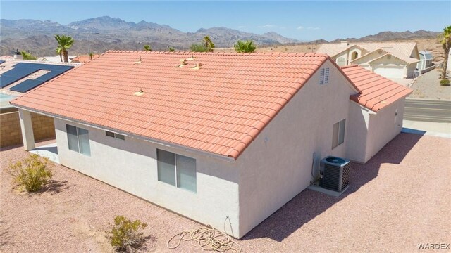 view of home's exterior featuring central AC, a mountain view, a tiled roof, and stucco siding