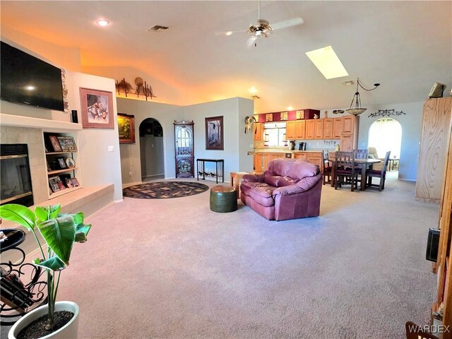 living room with vaulted ceiling with skylight, light colored carpet, baseboards, and visible vents