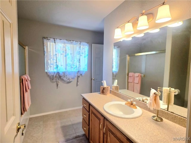 bathroom with a shower with shower door, tile patterned floors, vanity, and baseboards