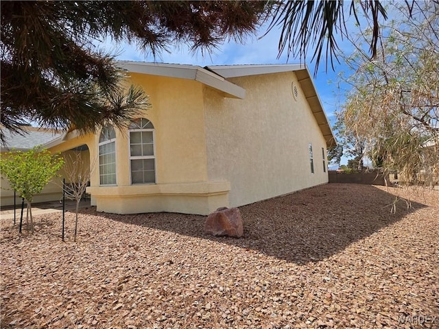 view of home's exterior with fence and stucco siding