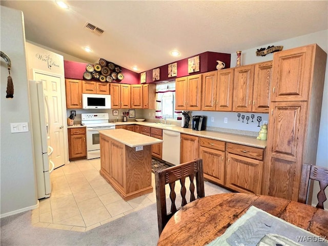 kitchen featuring visible vents, a sink, light countertops, white appliances, and a kitchen island