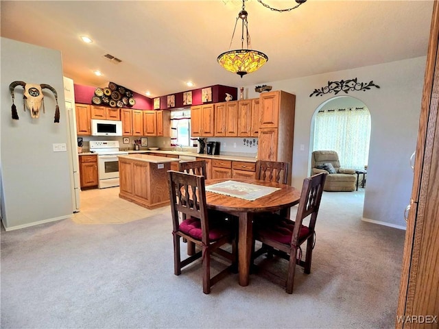 dining room with visible vents, baseboards, arched walkways, light colored carpet, and lofted ceiling