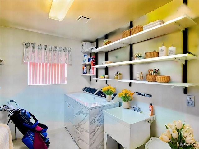 laundry room featuring washer and clothes dryer, visible vents, laundry area, and a sink