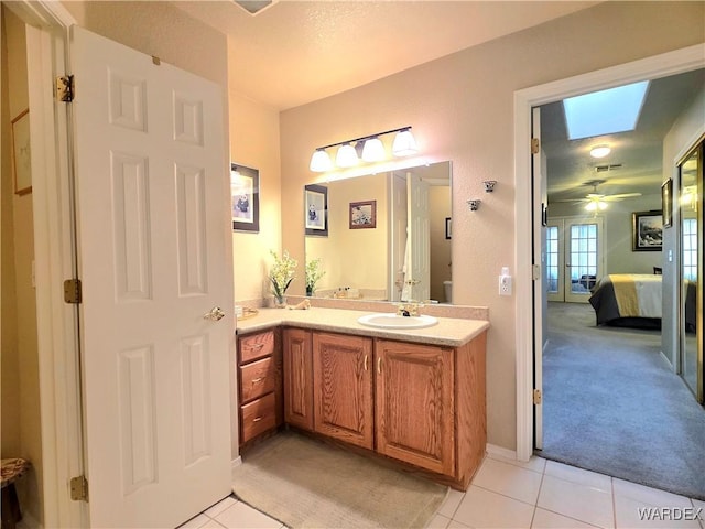 ensuite bathroom with a skylight, connected bathroom, tile patterned flooring, and vanity