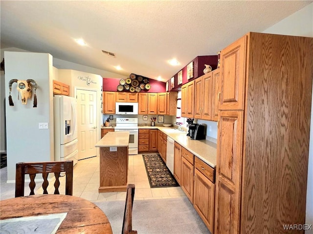 kitchen featuring visible vents, a sink, light countertops, white appliances, and lofted ceiling