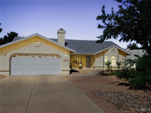 ranch-style house with a chimney, a garage, stucco siding, and driveway