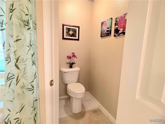 bathroom featuring tile patterned flooring, curtained shower, baseboards, and toilet