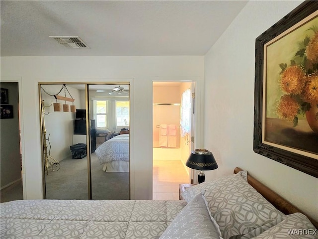 bedroom with carpet, visible vents, a closet, and ensuite bathroom
