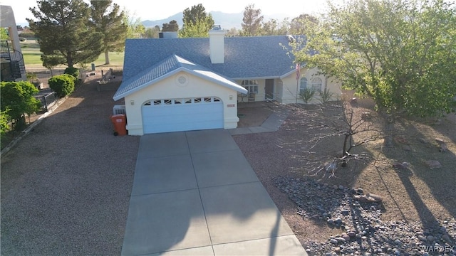 ranch-style home featuring concrete driveway, stucco siding, a chimney, a garage, and a shingled roof