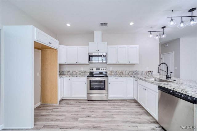 kitchen featuring stainless steel appliances, a sink, white cabinets, and pendant lighting