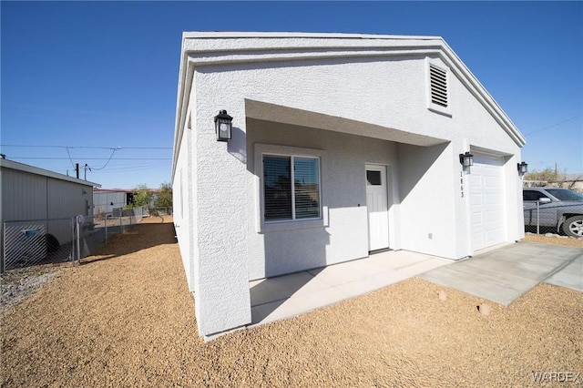 back of property with a garage, fence, and stucco siding