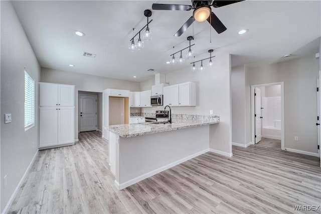 kitchen featuring light stone counters, visible vents, appliances with stainless steel finishes, white cabinetry, and a peninsula