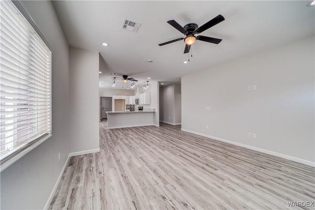 unfurnished living room featuring ceiling fan, light wood-type flooring, visible vents, and baseboards