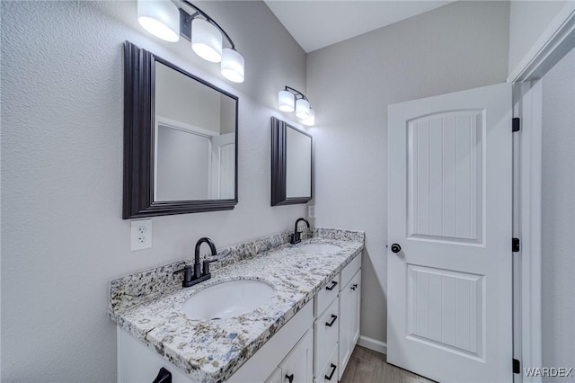 bathroom featuring double vanity, a sink, and baseboards