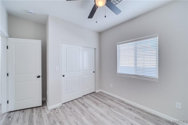 unfurnished bedroom featuring light wood finished floors, a closet, a ceiling fan, and baseboards