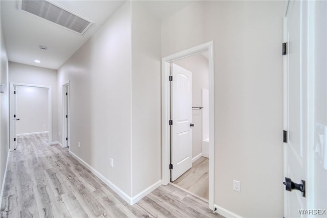 hall featuring visible vents, light wood-style flooring, and baseboards