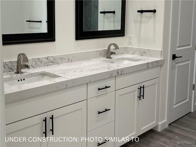 full bath with double vanity, wood finished floors, and a sink