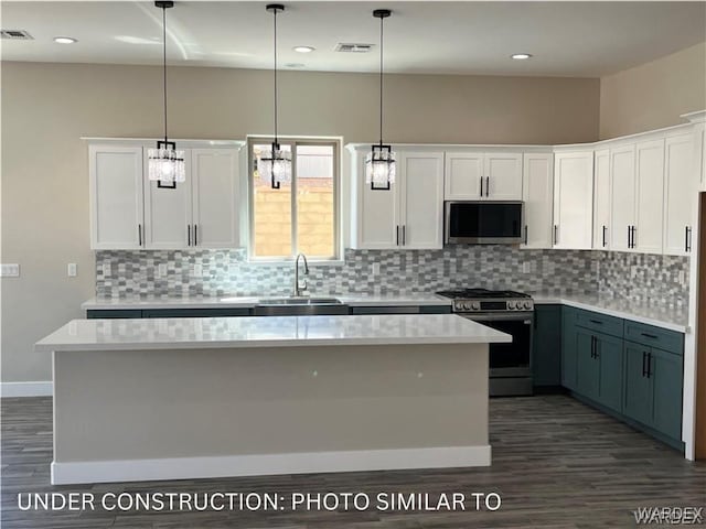 kitchen with stainless steel appliances, pendant lighting, light countertops, and white cabinets