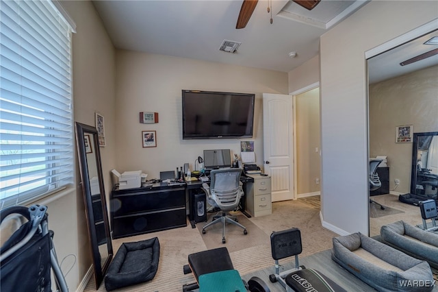 home office featuring visible vents, baseboards, a ceiling fan, and light colored carpet