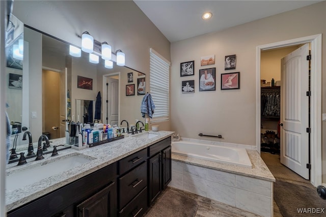 bathroom featuring a garden tub, double vanity, and a sink