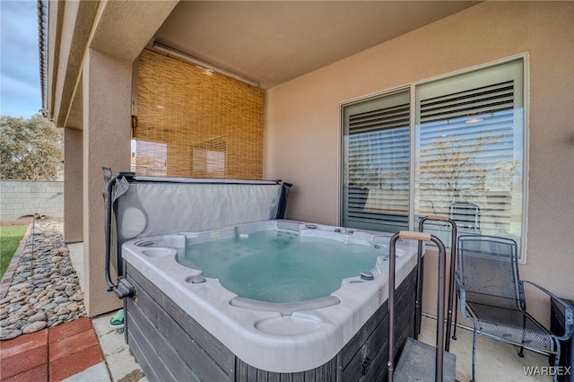 view of patio with fence and a hot tub