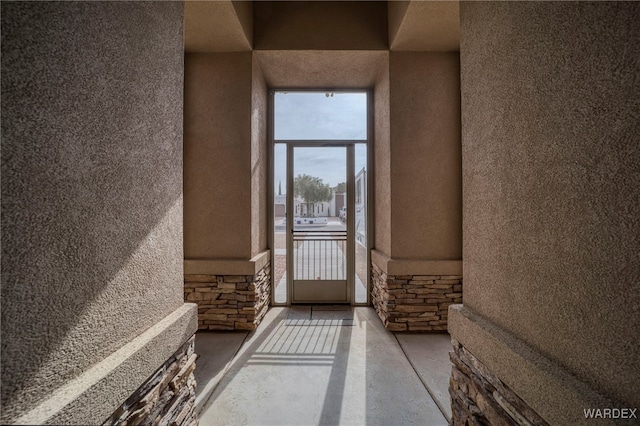 view of exterior entry featuring stone siding and stucco siding