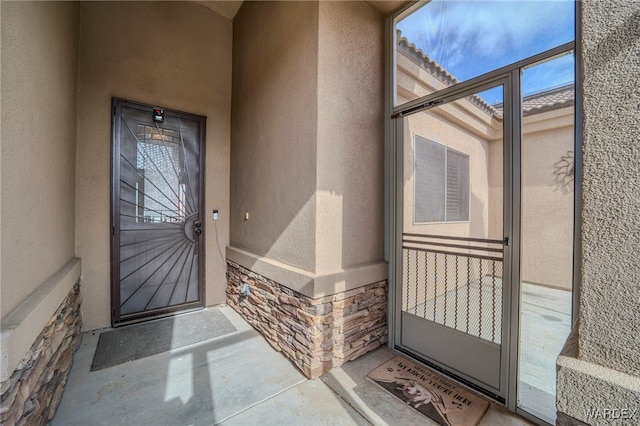 property entrance with stone siding and stucco siding