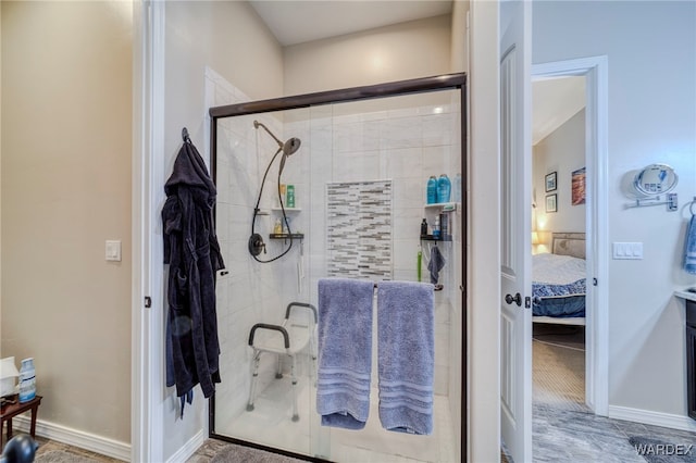 ensuite bathroom featuring a stall shower, connected bathroom, and baseboards