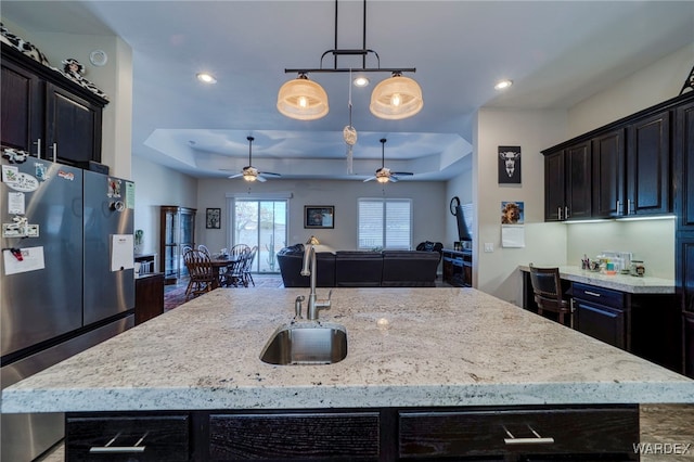 kitchen with freestanding refrigerator, open floor plan, a sink, and an island with sink