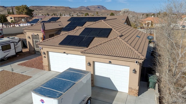 view of front of house with stucco siding, a mountain view, solar panels, and a tiled roof