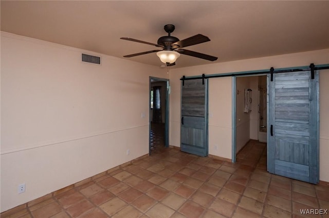 unfurnished bedroom with a barn door, visible vents, a ceiling fan, and a walk in closet