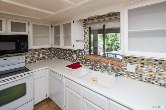 kitchen with backsplash, light countertops, a sink, and white appliances