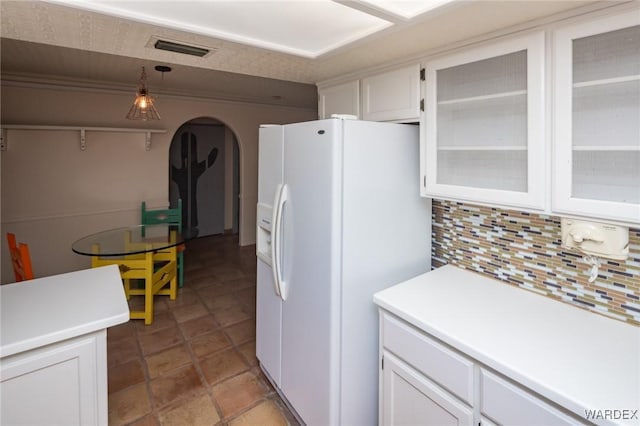 kitchen featuring white fridge with ice dispenser, visible vents, white cabinets, and decorative backsplash