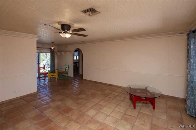 empty room with arched walkways, visible vents, ornamental molding, and ceiling fan