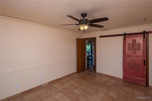 spare room with a barn door, ornamental molding, and ceiling fan