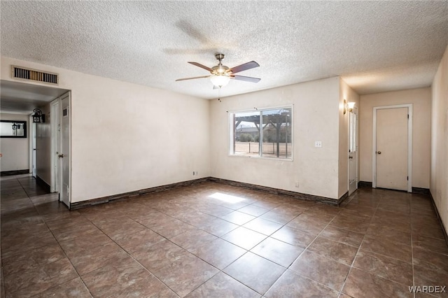 tiled empty room with visible vents, ceiling fan, a textured ceiling, and baseboards