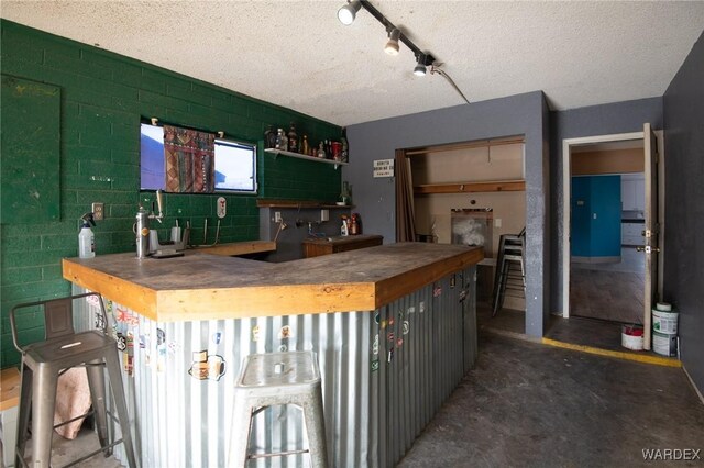 kitchen featuring concrete flooring, concrete block wall, and a textured ceiling