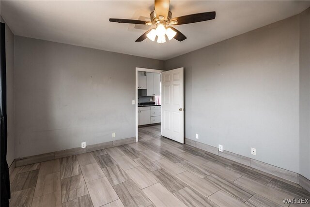 empty room featuring a ceiling fan and baseboards