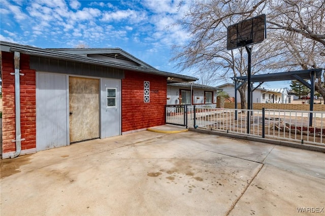 view of side of property with a patio area, fence, and brick siding