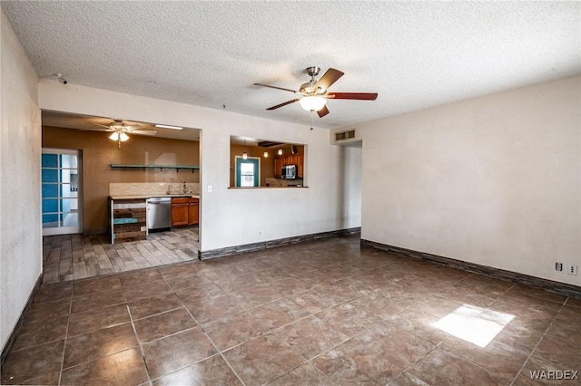 unfurnished living room with baseboards, visible vents, a ceiling fan, dark tile patterned flooring, and a textured ceiling