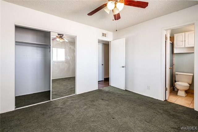 unfurnished bedroom with a textured ceiling, a closet, carpet flooring, and visible vents