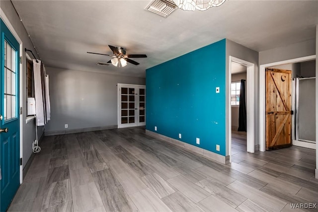 unfurnished living room with wood finished floors, visible vents, and a barn door