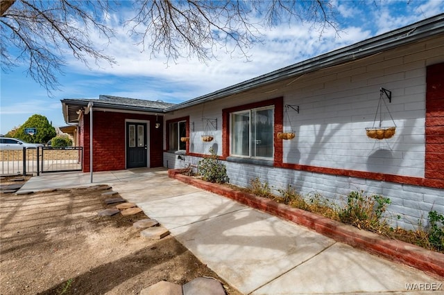 doorway to property with a gate, fence, and brick siding