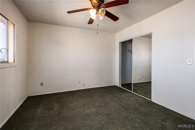 unfurnished bedroom featuring a ceiling fan, a closet, dark carpet, and a textured ceiling