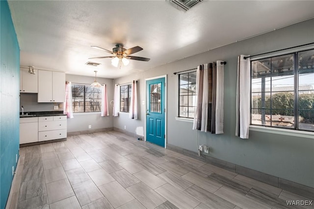 interior space featuring dark countertops, white cabinetry, visible vents, and a ceiling fan