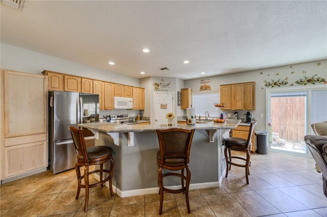 1919 Richardo Ave, Bullhead City, AZ 86442 - kitchen featuring appliances with stainless steel finishes, light stone counters, a breakfast bar area, a center island with sink, and recessed lighting
