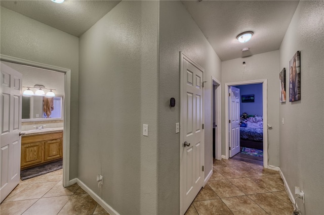 1919 Richardo Ave, Bullhead City, AZ 86442 - hallway featuring a textured wall, a sink, light tile patterned floors, a textured ceiling, and baseboards