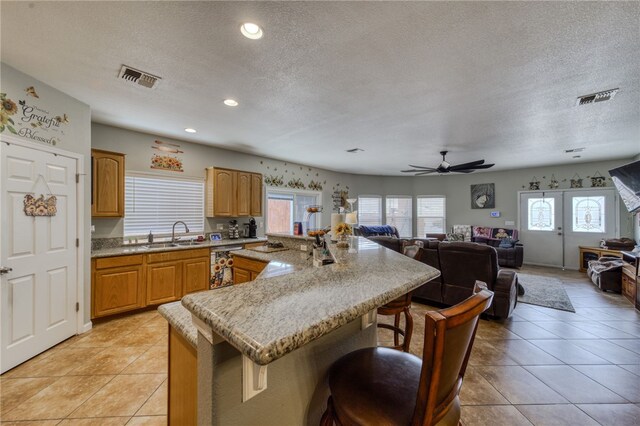 1919 Richardo Ave, Bullhead City, AZ 86442 - kitchen featuring a textured ceiling, a sink, a breakfast bar area, dishwashing machine, and light tile patterned flooring