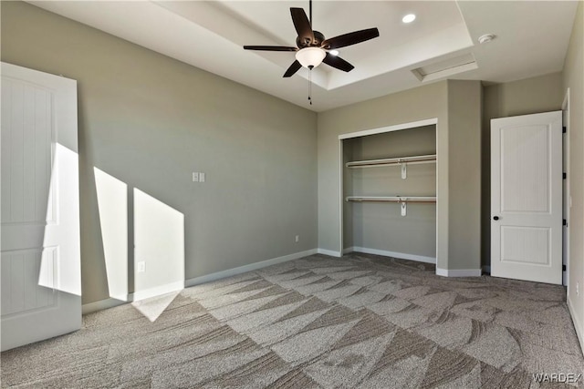 unfurnished bedroom with light carpet, baseboards, a closet, a tray ceiling, and attic access